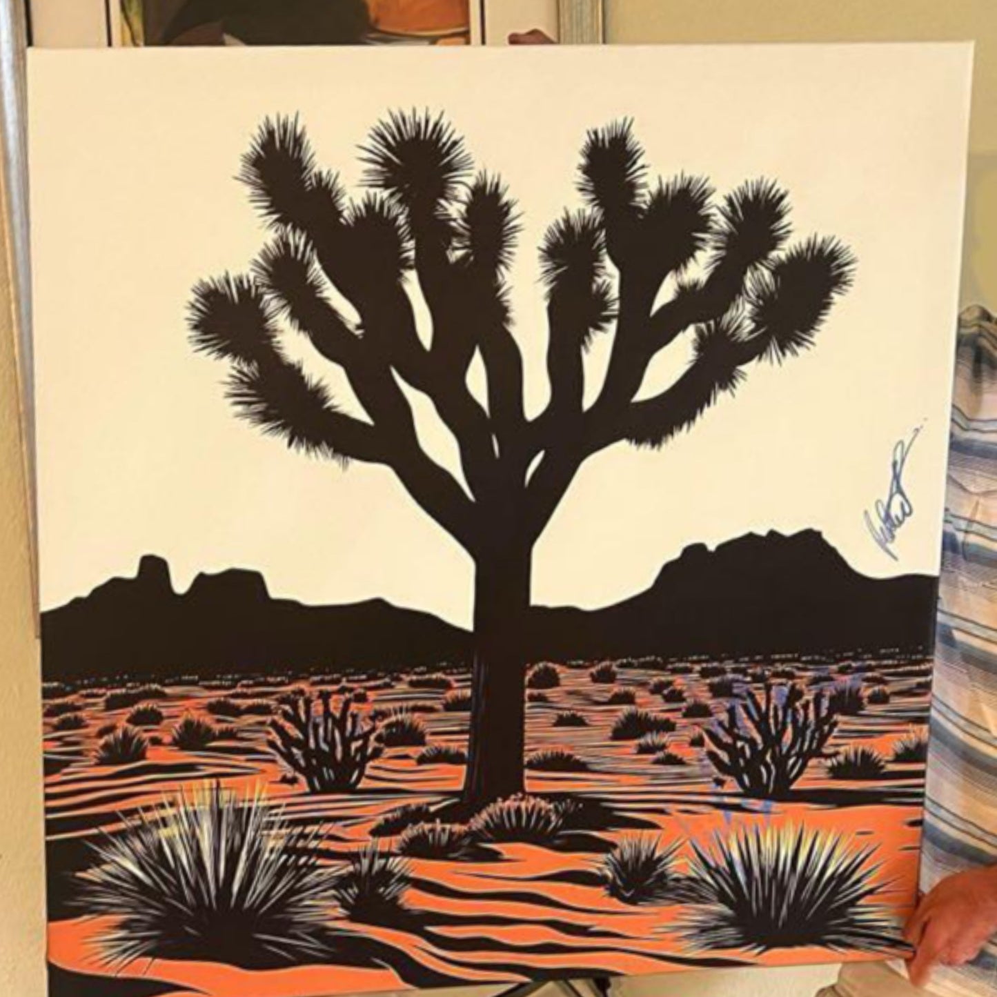 Artistic depiction of a Joshua tree with a desert landscape in black and orange.